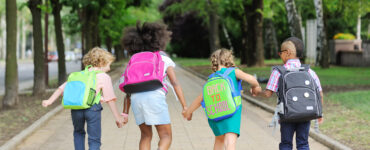 small schoolchildren with colorful school bags and backpacks run to school. Back to school, education, elementary school.