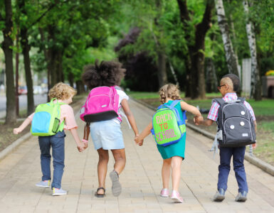 small schoolchildren with colorful school bags and backpacks run to school. Back to school, education, elementary school.