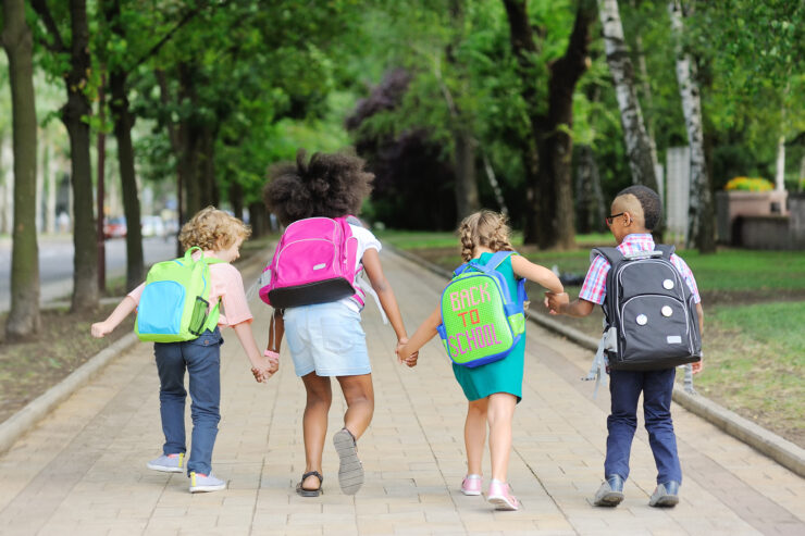 small schoolchildren with colorful school bags and backpacks run to school. Back to school, education, elementary school.