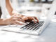 Hands of unrecognisable businesswoman typing on her laptop at cafe.