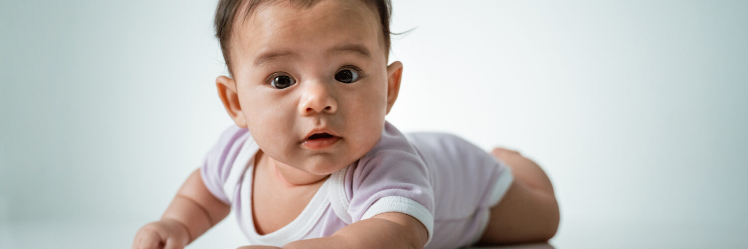 baby laying on her belly. tummy time cute baby in studio portrait on white background