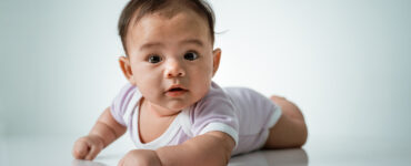 baby laying on her belly. tummy time cute baby in studio portrait on white background