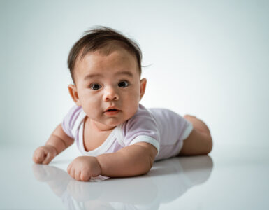 baby laying on her belly. tummy time cute baby in studio portrait on white background